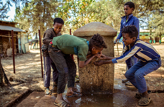 Happy kids drinking water from a fresh water source